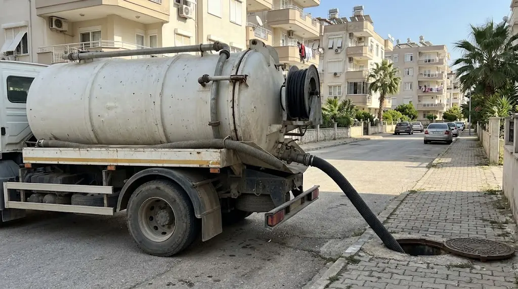 Apartman sokağında vidanjör tankı ve bacaya uzanan hortum